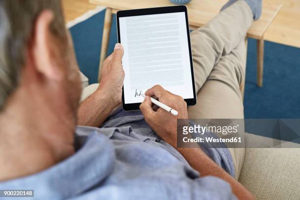 mature man signing digital contract on tablet - signing tablet stock pictures, royalty-free photos & images