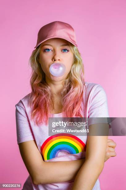 portrait of cool young woman with bubble gum in front of pink background - purple shirt fotografías e imágenes de stock