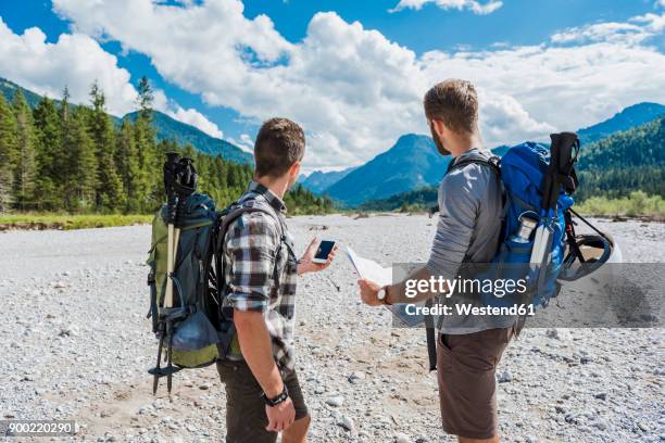 germany, bavaria, two hikers standing in dry creek bed orientating with cell phone and map - two young men stock pictures, royalty-free photos & images