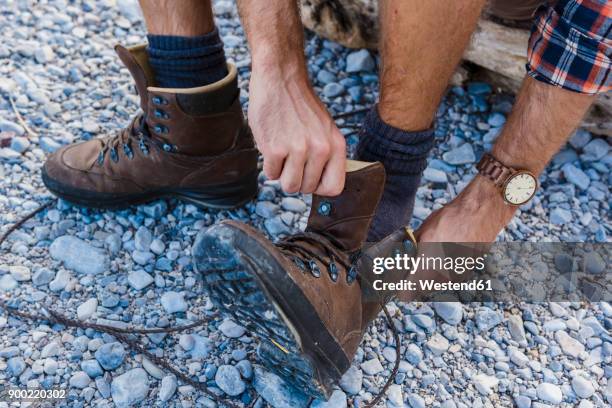 hiker putting on his shoes, partial view - hiking boot stock pictures, royalty-free photos & images