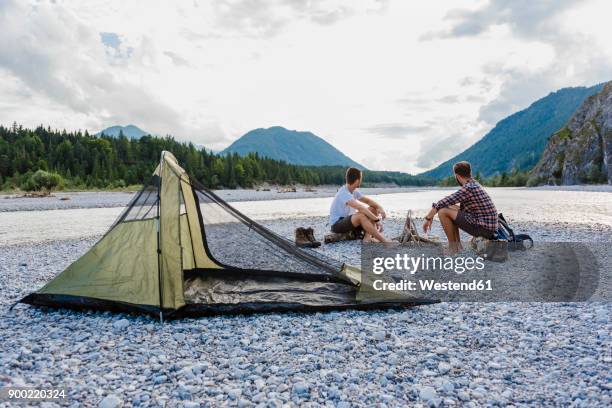 germany, bavaria, two hikers camping on gravel bank looking at view - río isar fotografías e imágenes de stock