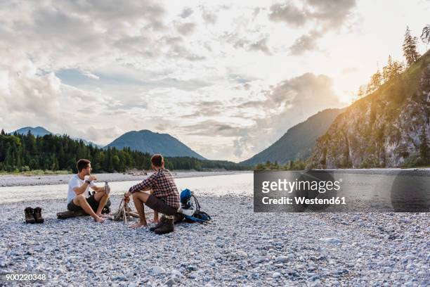 germany, bavaria, two hikers having a rest on gravel bank in the evening - bavaria summer stock pictures, royalty-free photos & images