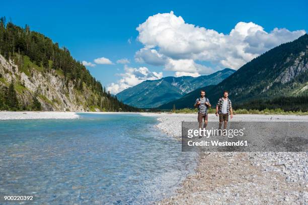 germany, bavaria, two hikers walking at riverside - riverbank stock-fotos und bilder