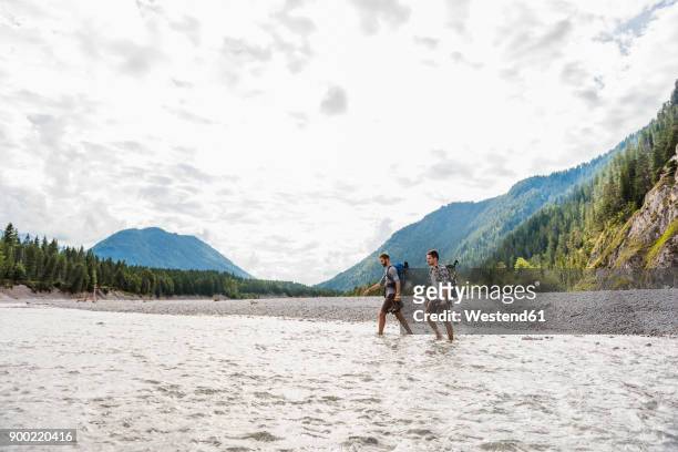 germany, bavaria, two hikers with backpacks crossing isar river - wading river stock pictures, royalty-free photos & images