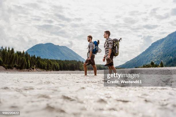 germany, bavaria, two hikers with backpacks crossing isar river - crossing river stock pictures, royalty-free photos & images