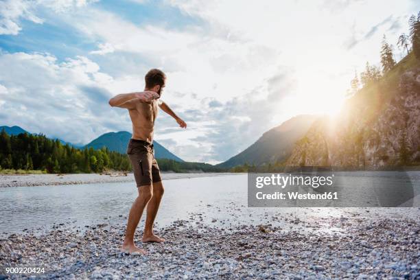 germany, bavaria, man standing at riverside throwing stone - throwing rocks stock pictures, royalty-free photos & images