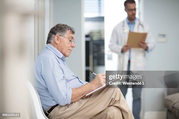 patient filling in file in medical practice - wartezimmer stock-fotos und bilder