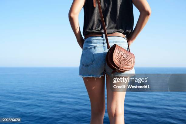 back view of woman looking at the sea, partial view - leather shorts stock pictures, royalty-free photos & images