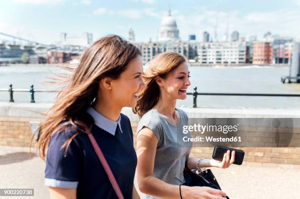 uk, london, two women walking along the banks of the thames river - river thames walk stock pictures, royalty-free photos & images