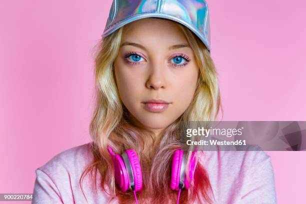 portrait of young woman with headphones and basecap in front of pink background - pink eyeshadow stock-fotos und bilder