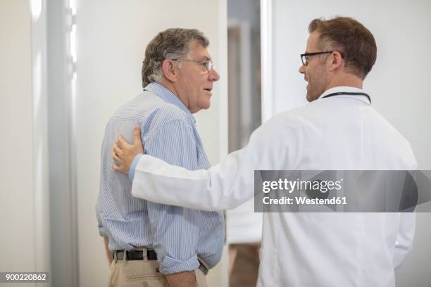 doctor talking to senior patient in medical practice - senior blaumann stock-fotos und bilder