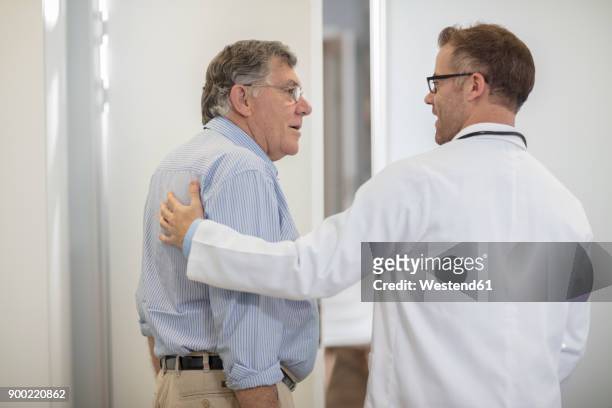 doctor talking to senior patient in medical practice - doctor behind stock pictures, royalty-free photos & images