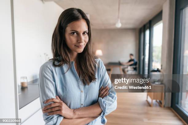 portrait of smiling woman at home with man in background - blouse man stockfoto's en -beelden