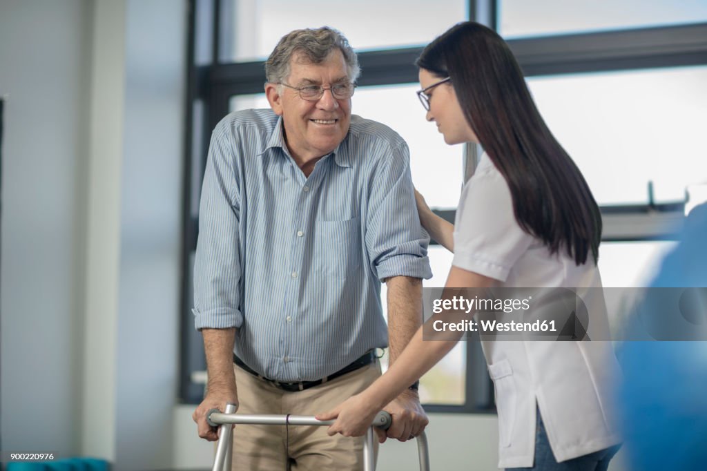Nurse helping senior patient with walking frame