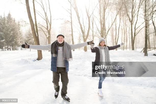 happy senior couple ice skating - アイススケート ストックフォトと画像