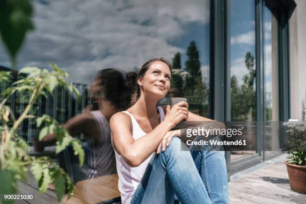 smiling woman relaxing on balcony - sonnenlicht stock-fotos und bilder