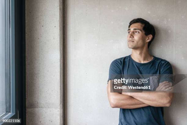 young man looking out of window - beschaulichkeit stock-fotos und bilder