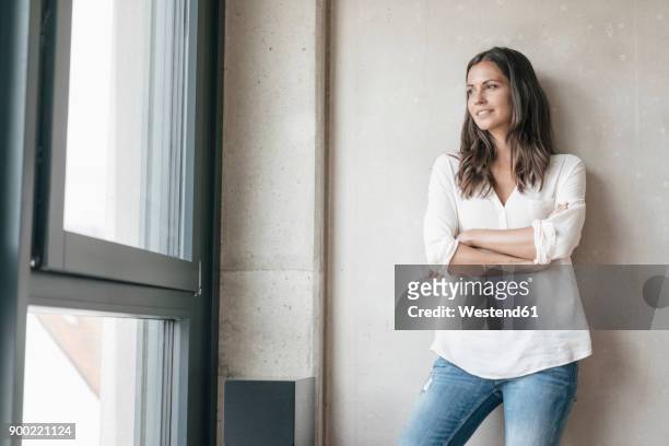 smiling woman looking out of window - tre quarti foto e immagini stock