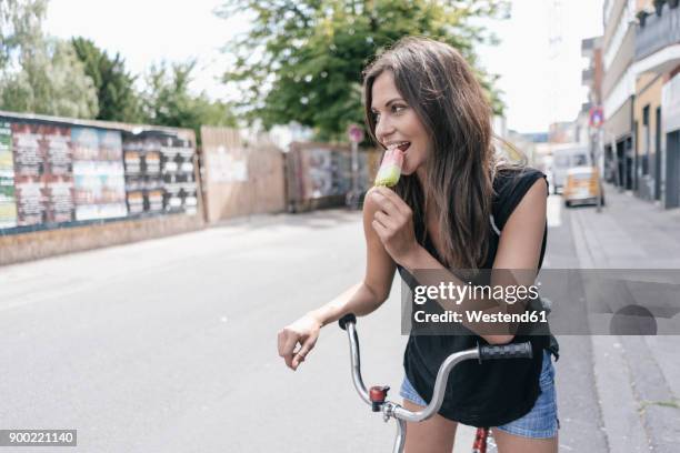 woman with bicycle eating ice lolly - woman ice cream stock pictures, royalty-free photos & images