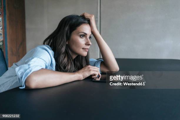 woman with tablet leaning on table - aburrimiento fotografías e imágenes de stock