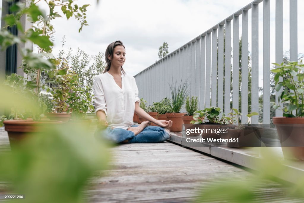 Woman sitting on balcony practicing yoga