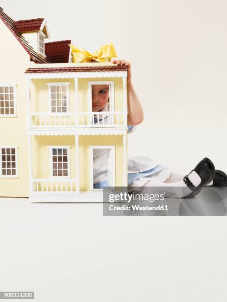 little girl dressed up as alice in wonderland behind doll's house - looking through a doll house photos et images de collection