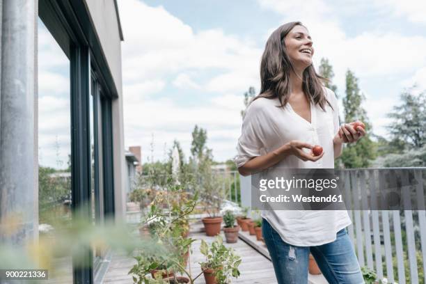 happy woman on balcony holding tomatoes - balcony vegetables stock pictures, royalty-free photos & images