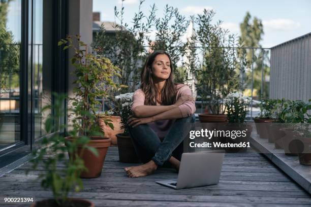 woman with laptop sitting on balcony - frau balkon stock-fotos und bilder