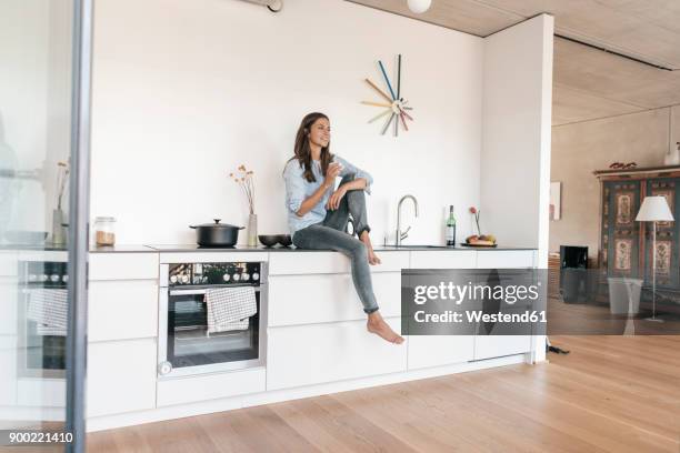 smiling woman relaxing in kitchen at home - kitchen coffee home stock-fotos und bilder