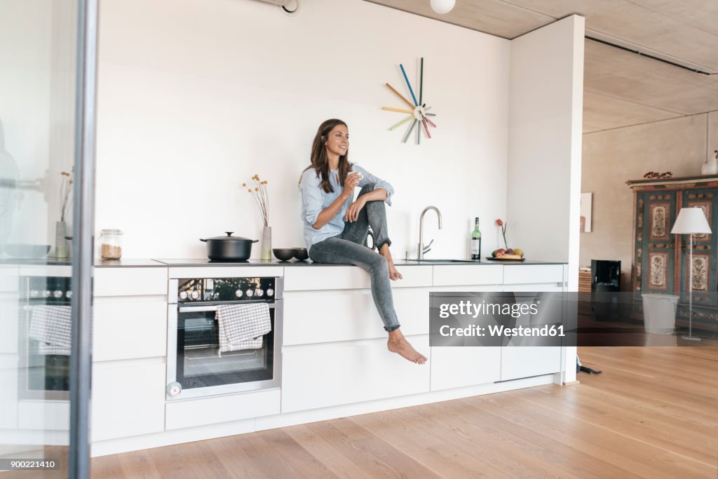 Smiling woman relaxing in kitchen at home