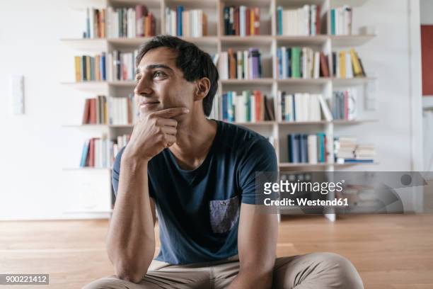 smiling young man at home looking sideways - contemplation home stock-fotos und bilder