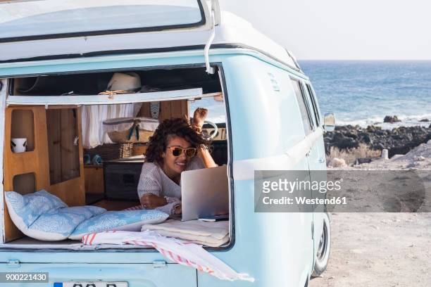 spain, tenerife, smiling woman looking at laptop in van - people carrier fotografías e imágenes de stock