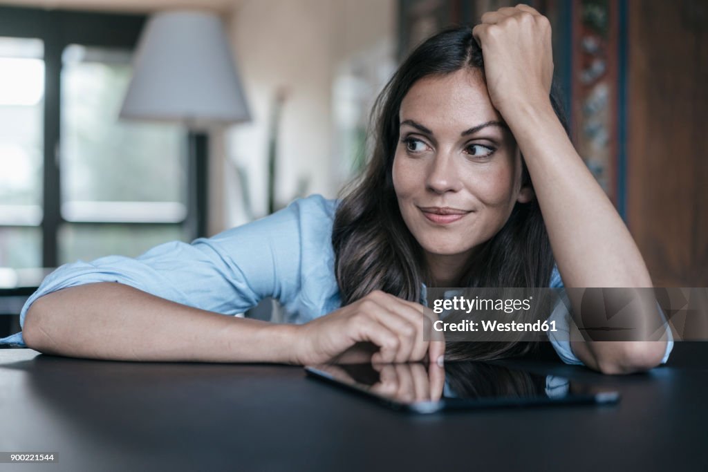 Woman with tablet leaning on table