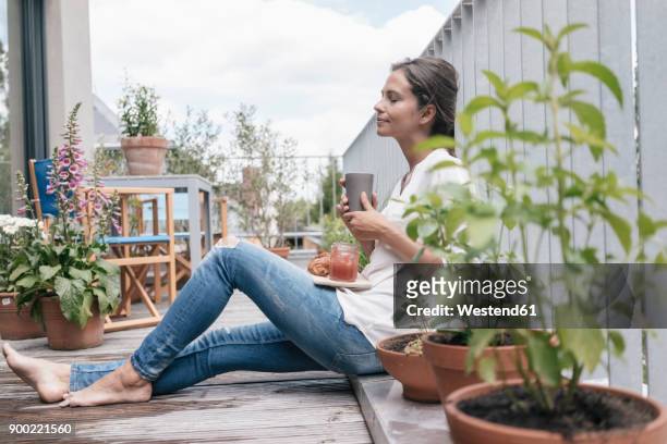 woman relaxing on balcony - evasión fotografías e imágenes de stock