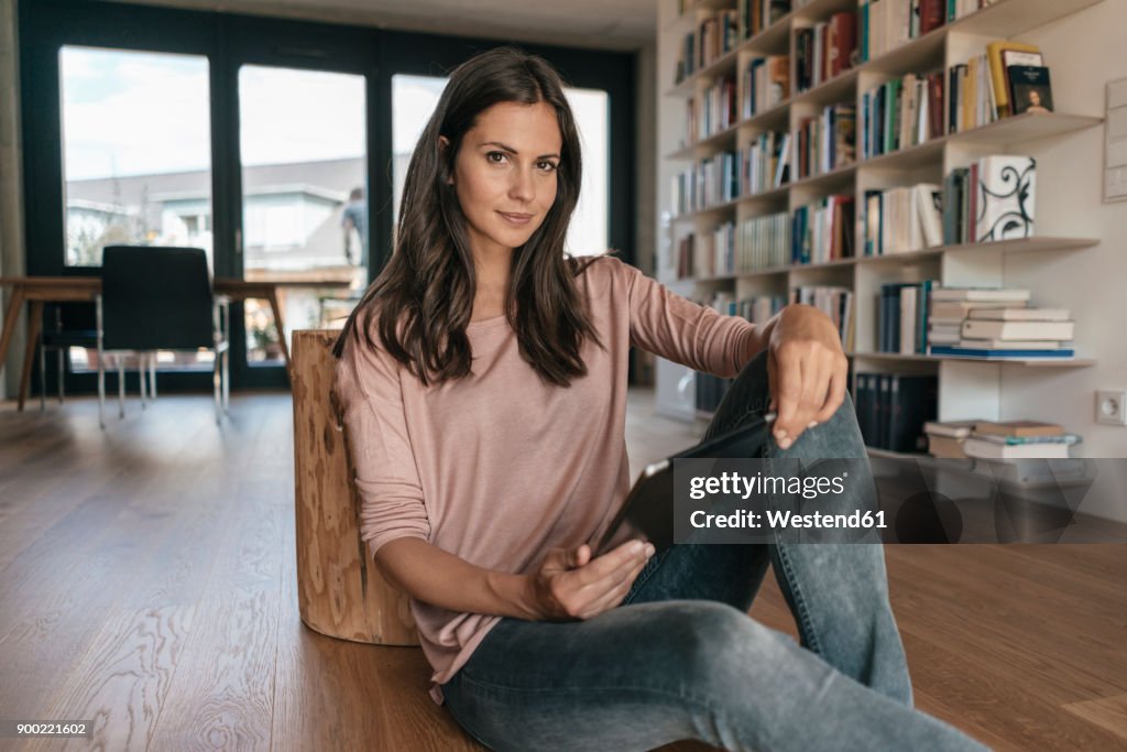 Portrait of woman relaxing at home holding tablet