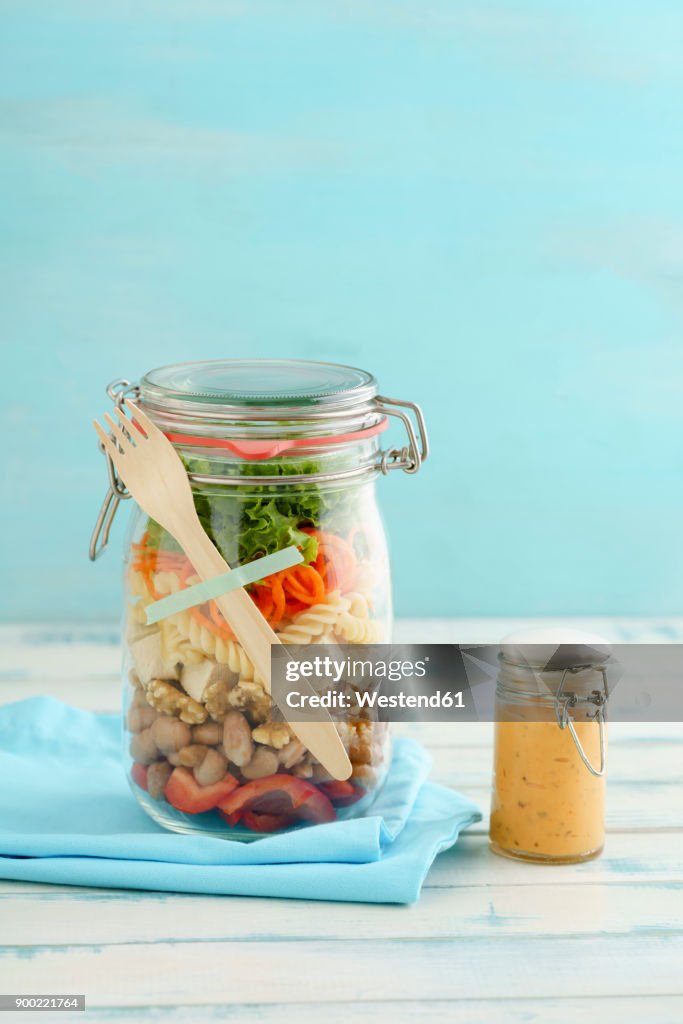 Preserving jar of vegan mixed salad with tofu and pasta and jar of cocktail sauce