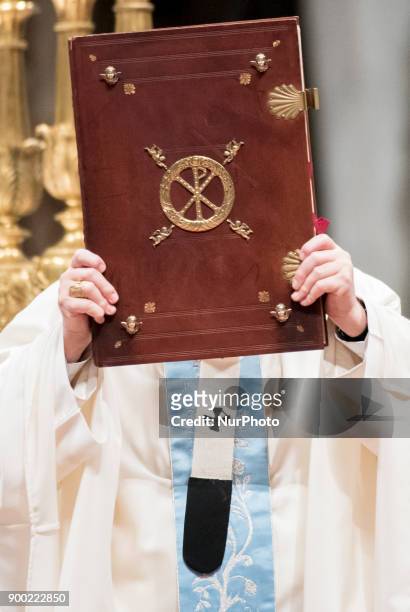 Pope Francis shows the Holy Book as he celebrates a new year's Mass in St. Peter's Basilica at the Vatican, Monday, Jan. 1, 2018.