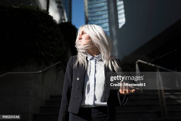 young businesswoman with windswept hair in the city - dyed red hair fotografías e imágenes de stock