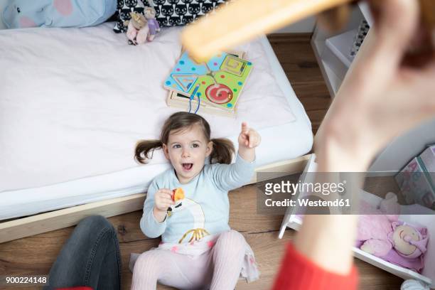 toddler girl pointing at mother's hand holding a toy plane - family with one child mother bonding family adult daughter focus on background leisure stock-fotos und bilder