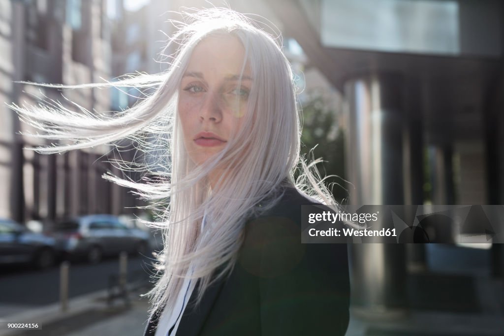 Portrait of young businesswoman with windswept hair in the city