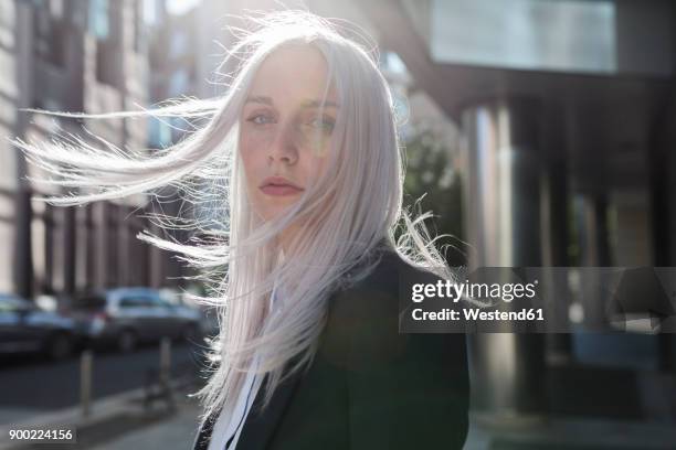 portrait of young businesswoman with windswept hair in the city - grey hair stockfoto's en -beelden