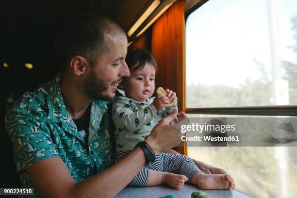 father giving a cookie to his baby girl while traveling by train - biscuit france stock pictures, royalty-free photos & images