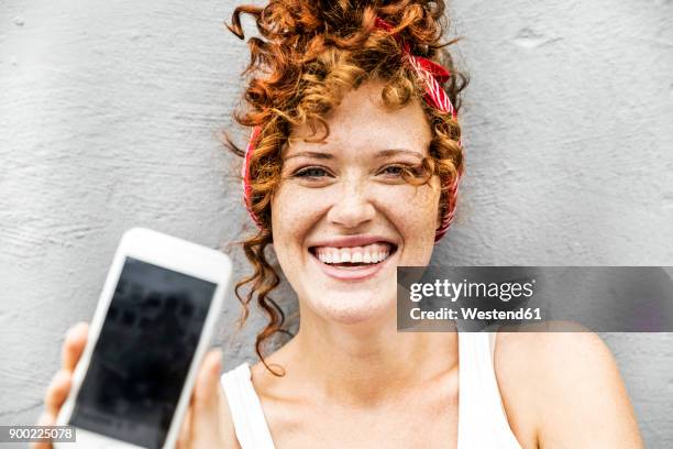 happy redheaded woman showing cell phone - tonen stockfoto's en -beelden