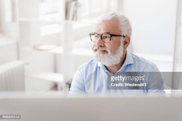 smiling mature man with beard and glasses at desk - person surrounded by computer screens stock pictures, royalty-free photos & images