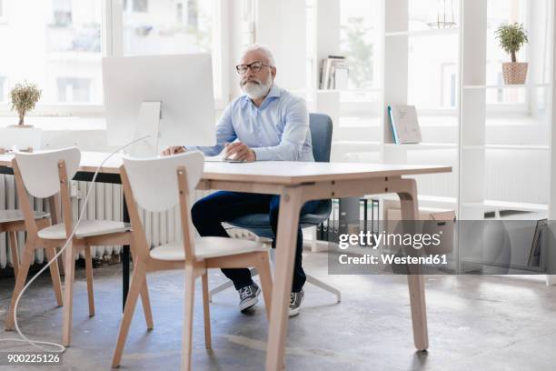 mature man with beard and glasses working at desk - person surrounded by computer screens stock pictures, royalty-free photos & images