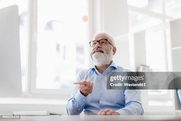 mature man with beard and glasses working at desk - person surrounded by computer screens stock pictures, royalty-free photos & images