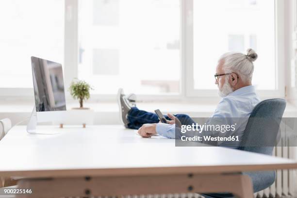 mature man with beard using cell phone at desk - person surrounded by computer screens stock pictures, royalty-free photos & images