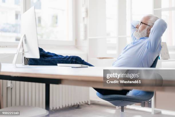 mature man with beard relaxing at desk - person surrounded by computer screens stock pictures, royalty-free photos & images