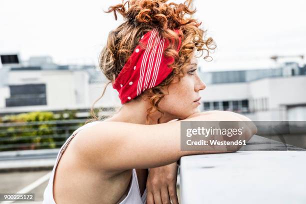 serious redheaded woman leaning on wall - stirnband stock-fotos und bilder