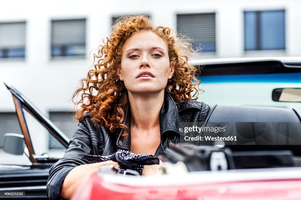 Portrait of confident redheaded woman in sports car